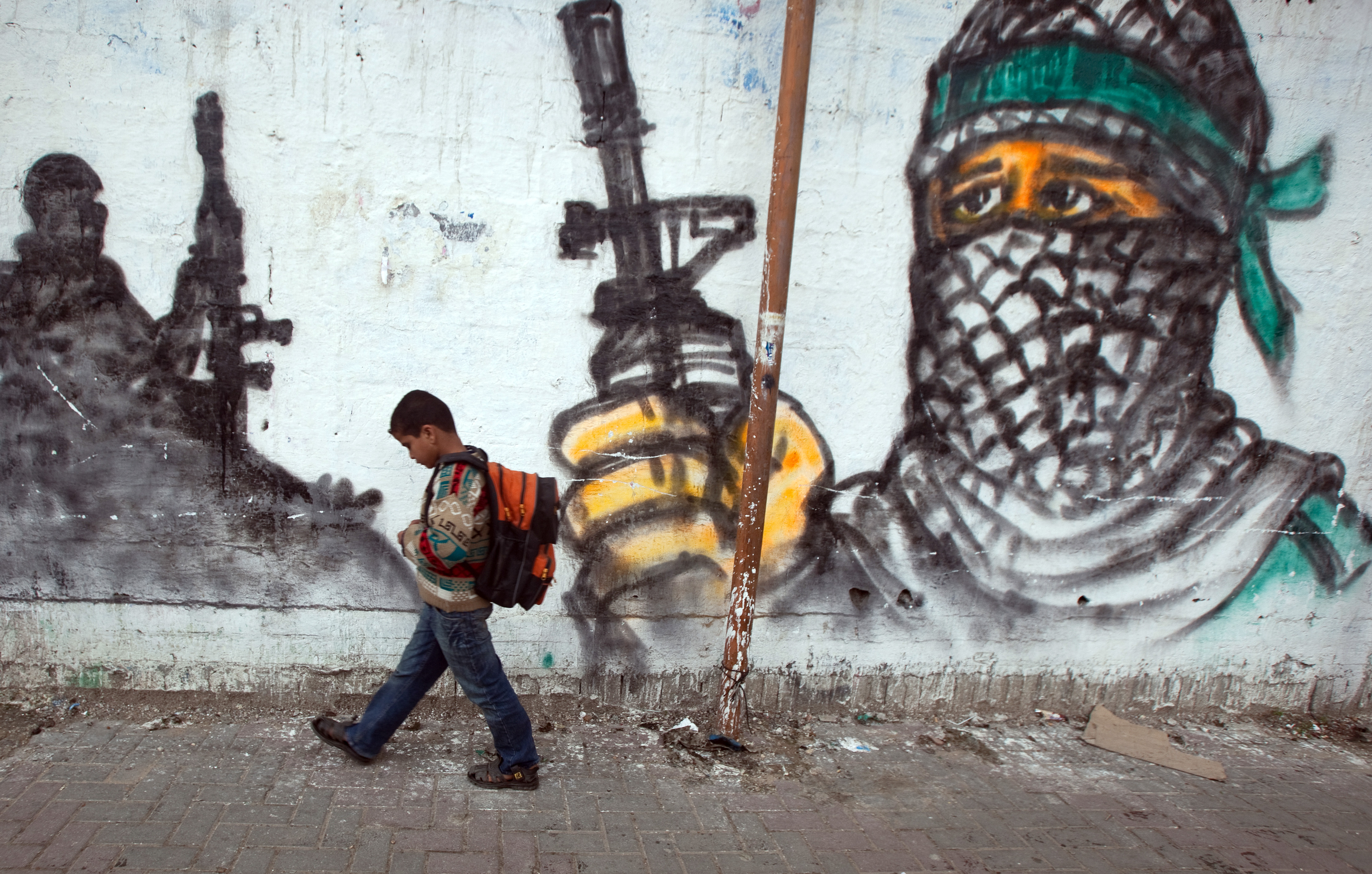 Palestinian boy passing by a grafitti as he walks to school at Jabalia area, northern Gaza Strip