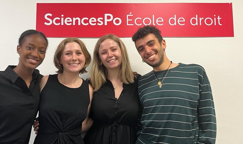 Four people standing in front of a banner reading SciencesPo Ecole de droit